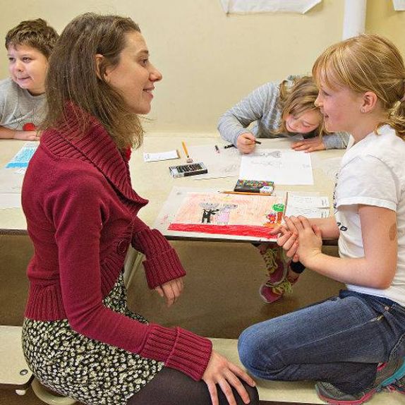 Sarah Hagen wearing red sweater, in classroom with student