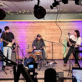 Andrew Savage and his band performing live for local sets in Austin, Texas, with Savage playing acoustic guitar, delivering a soulful folk rock performance.