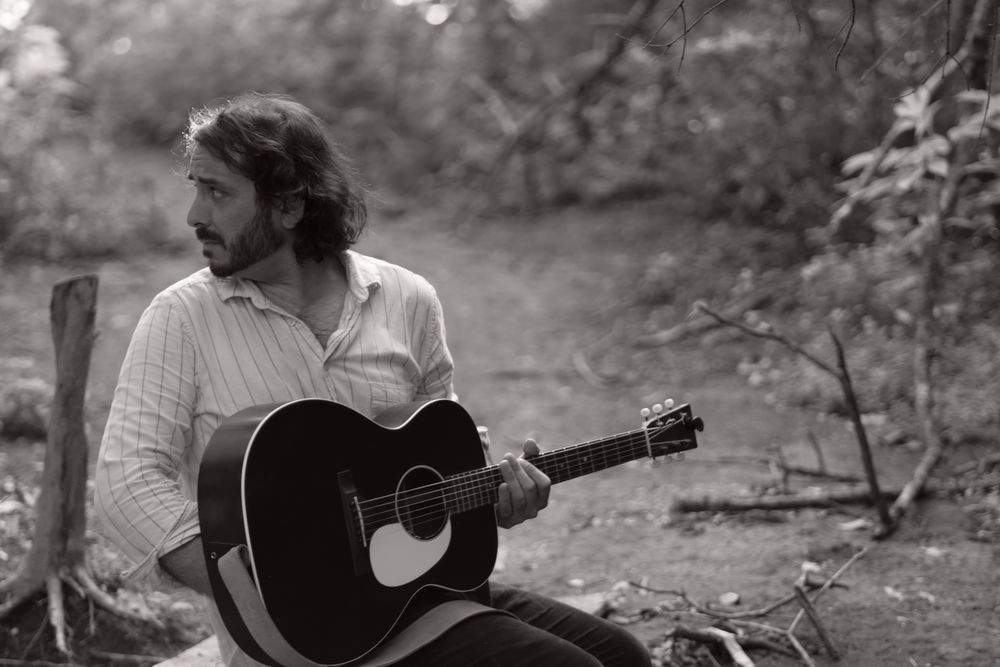 Andrew Savage indie folk singer songwriter from Austin Texas black and white promo photo with acoustic guitar