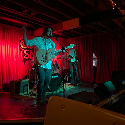 Andrew Savage and his band performing live at The Coral Snake in Austin, Texas, delivering an electrifying folk rock set in an intimate venue.