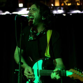 Andrew Savage performing live at Hole in the Wall in Austin, Texas, playing electric guitar and delivering a powerful rock performance.