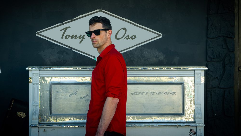 Tony Oso, Melbourne Florida musician, standing in front of a grand piano