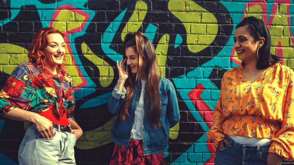 young women dressed in color against a painted mural