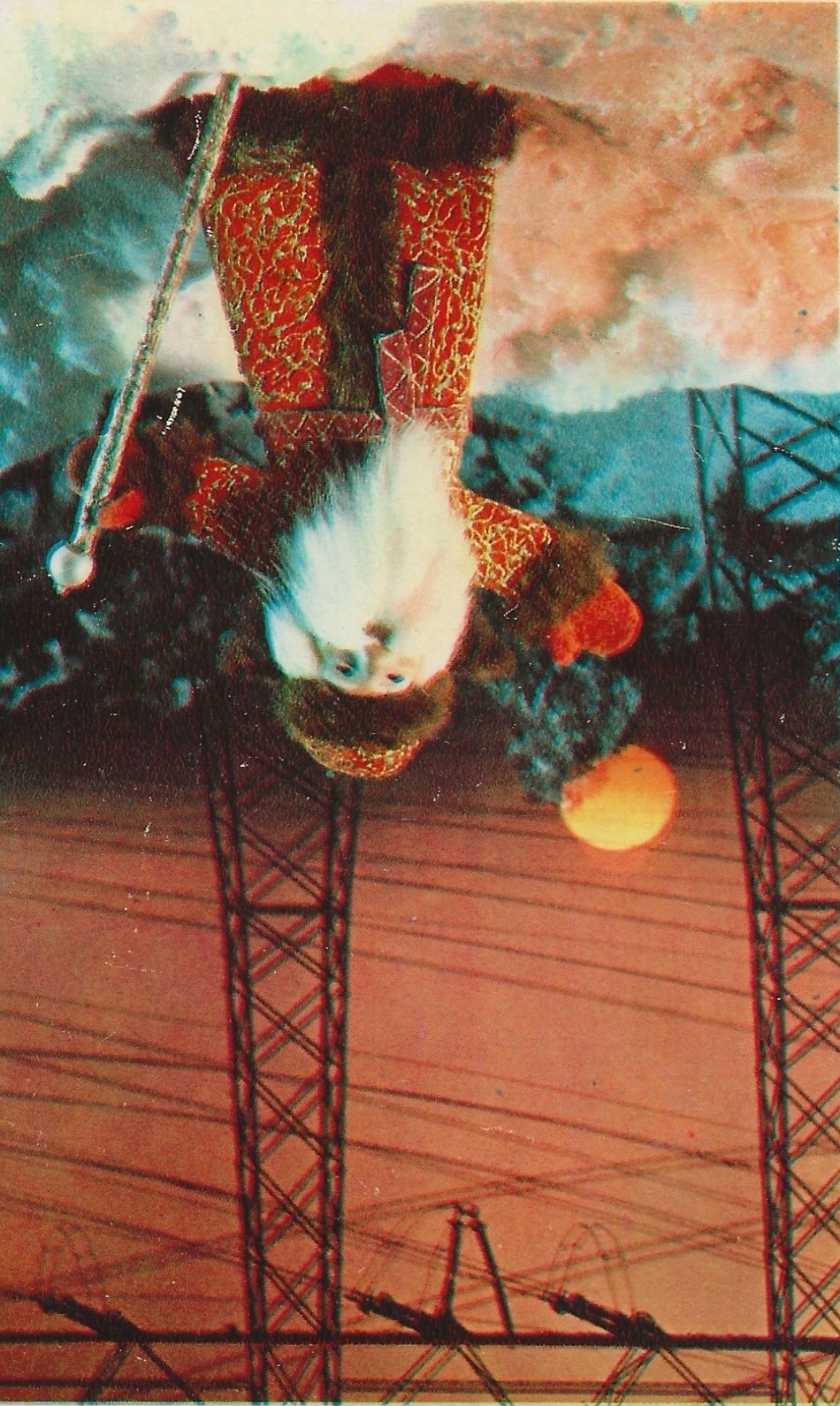 An old postcard of a Father Christmas figure waving in front of some pylons as the sun sets behind the snow. From Roberta Fidora's postcard collection.