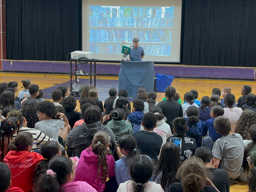 Library Boogie school assembly photo featuring Tom Knight performing music and puppetry