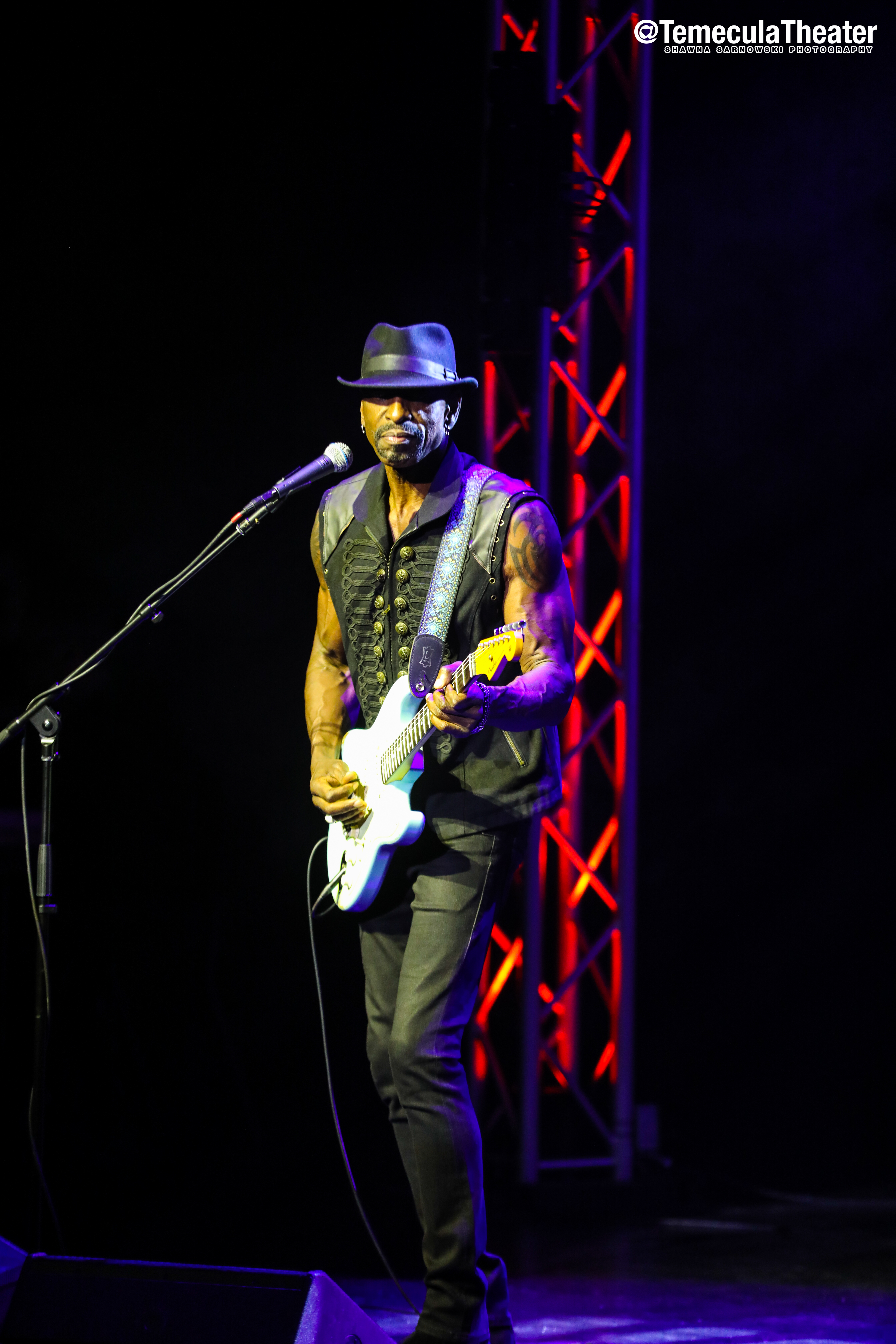 Dennis Jones performing on stage lit in red