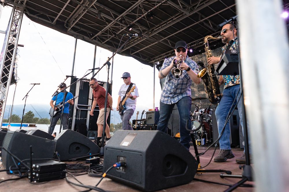 The Martini Shot performing at an outdoor Colorado festival with horns up front and large audience engagement