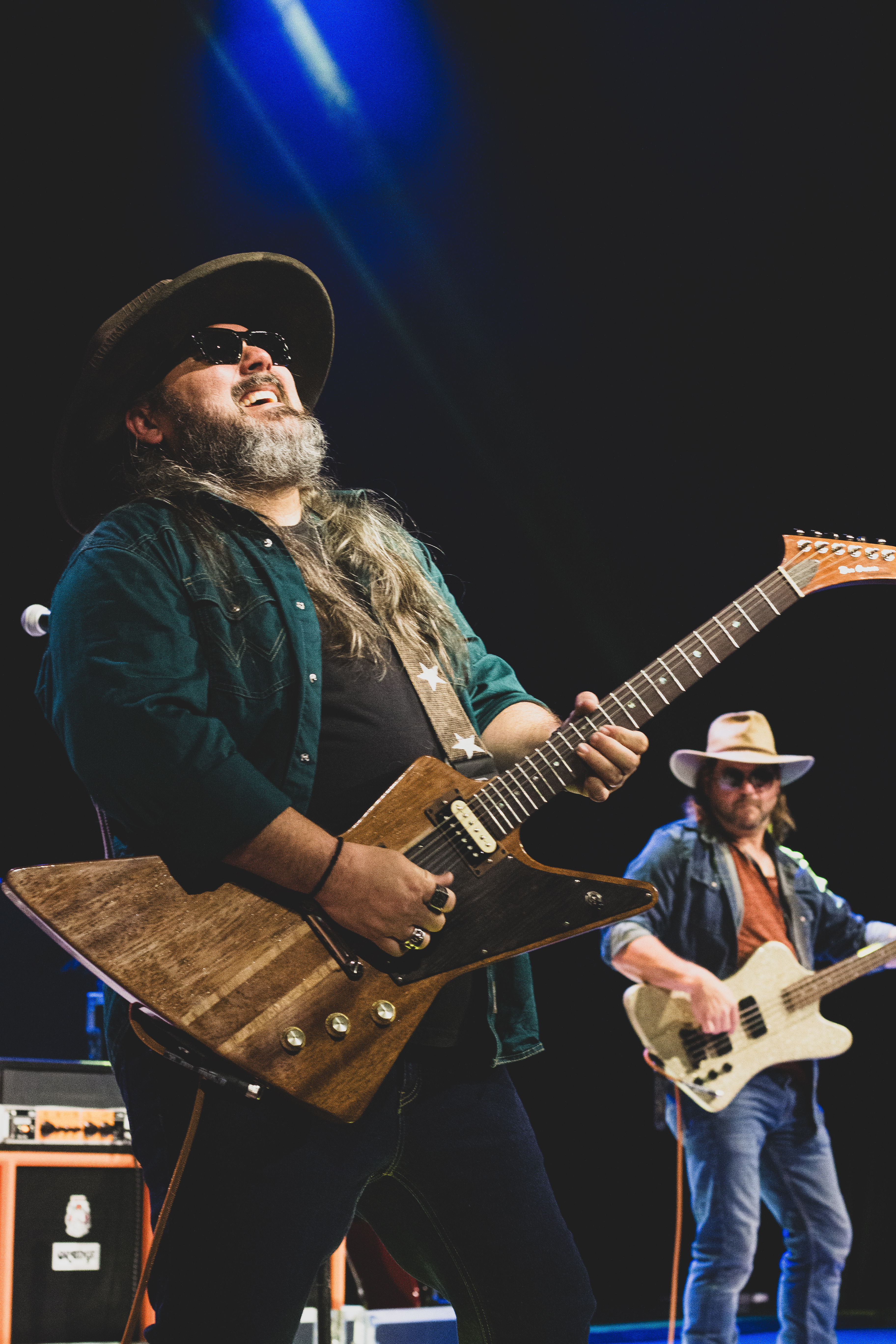 Derrick Dove singing and playing guitar under blue stage lights