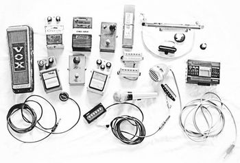 Pedals, pickups and paraphernalia. Original VOX Wah-wah and pedals, Nighthawks button (upper right), hi-tech cassette recorder under that, loose pickups, acoustic pickups, bullet mic, Echo chromatic harmonica
