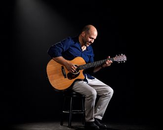 Claude Borges performing live with acoustic guitar.
