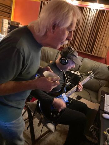 Phil leans in with bowl of soup in hand as John lays down a guitar track, Critical Misunderstandings On The Precipice session.
