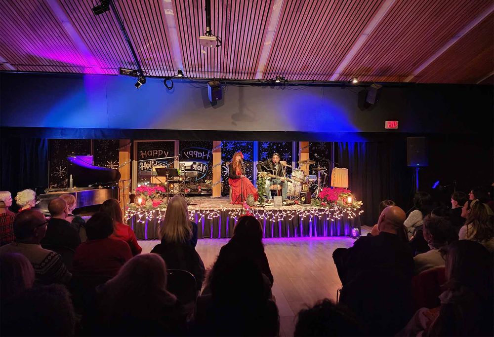 Heather Richards performing live before a seated audience at a holiday concert in an intimate theater setting.