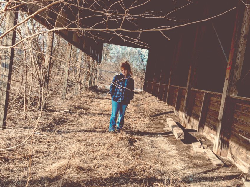 Heather Richards standing near an old weathered barn in rural Upstate New York in a soft atmospheric editorial portrait.