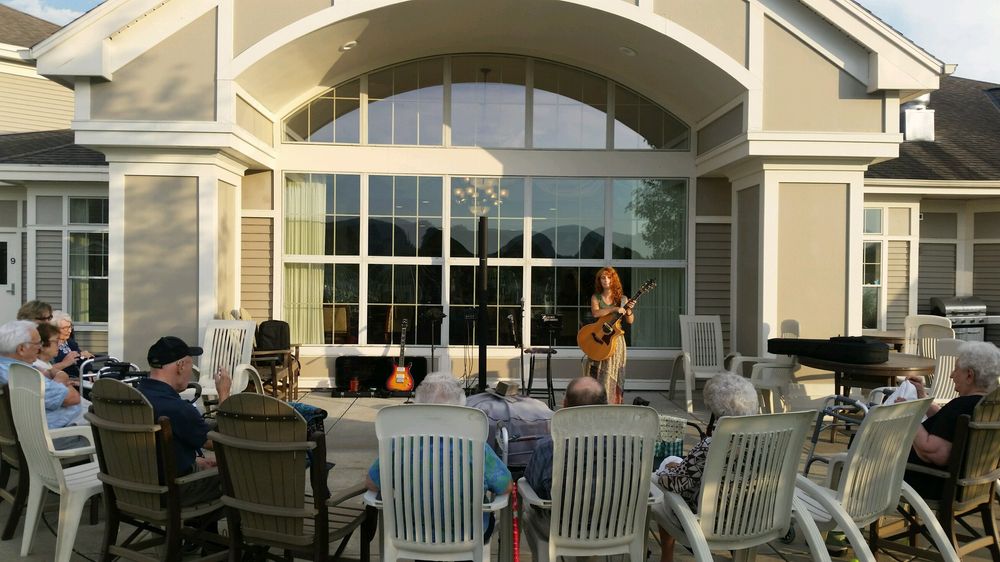 Heather Richards performing an evening outdoor acoustic concert in front of a live audience.