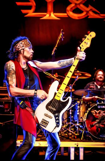 Aaron Leigh onstage with Y&T, with bass raised.
