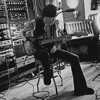 Aaron Leigh playing electric guitar in the studio.
