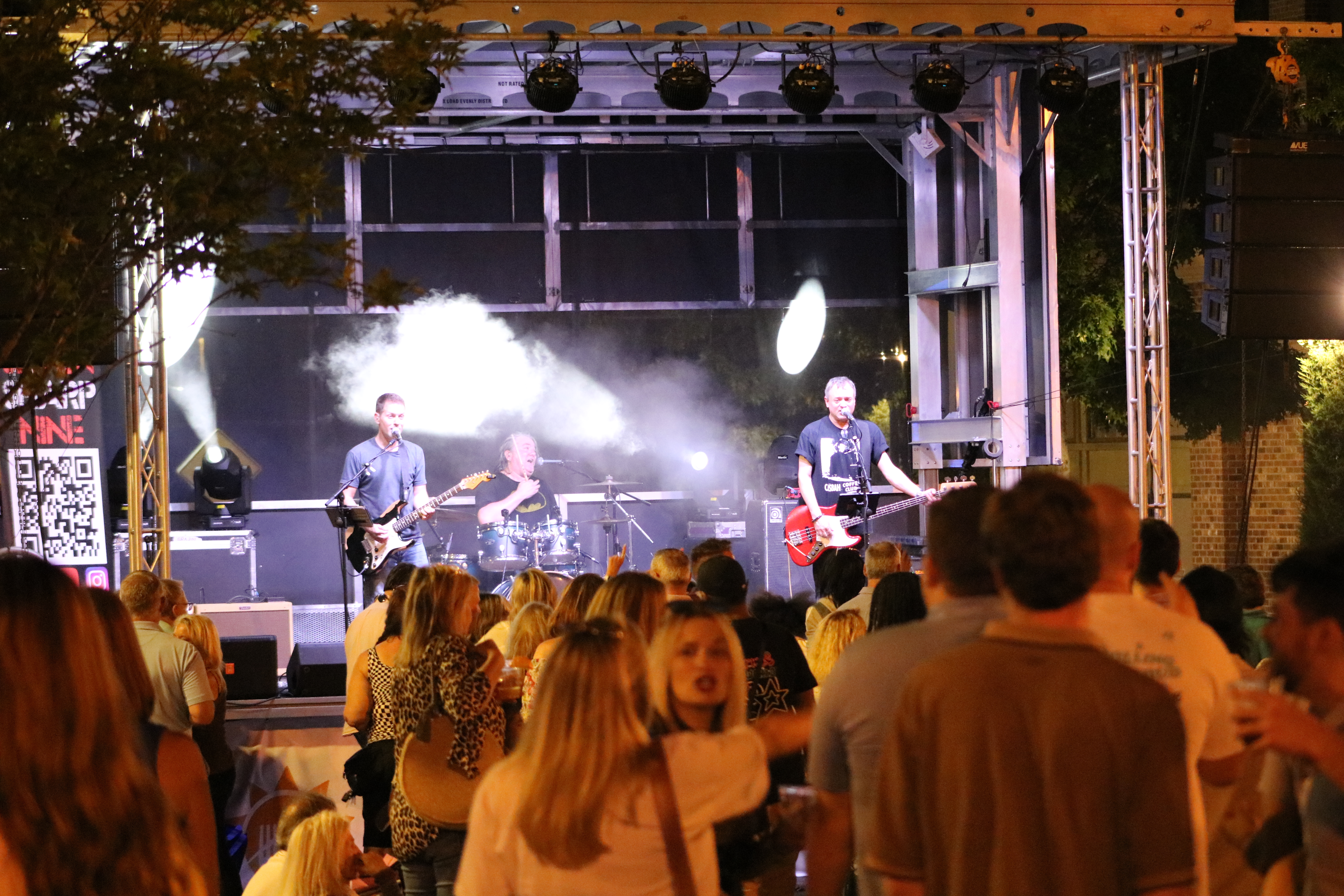 7 Sharp 9 three-piece performing outdoors at night for a dense crowd