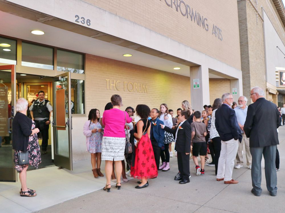 The Broome County Forum Theatre with Philharmonic patrons of many ages standing outside waiting to go in while a security guard watches