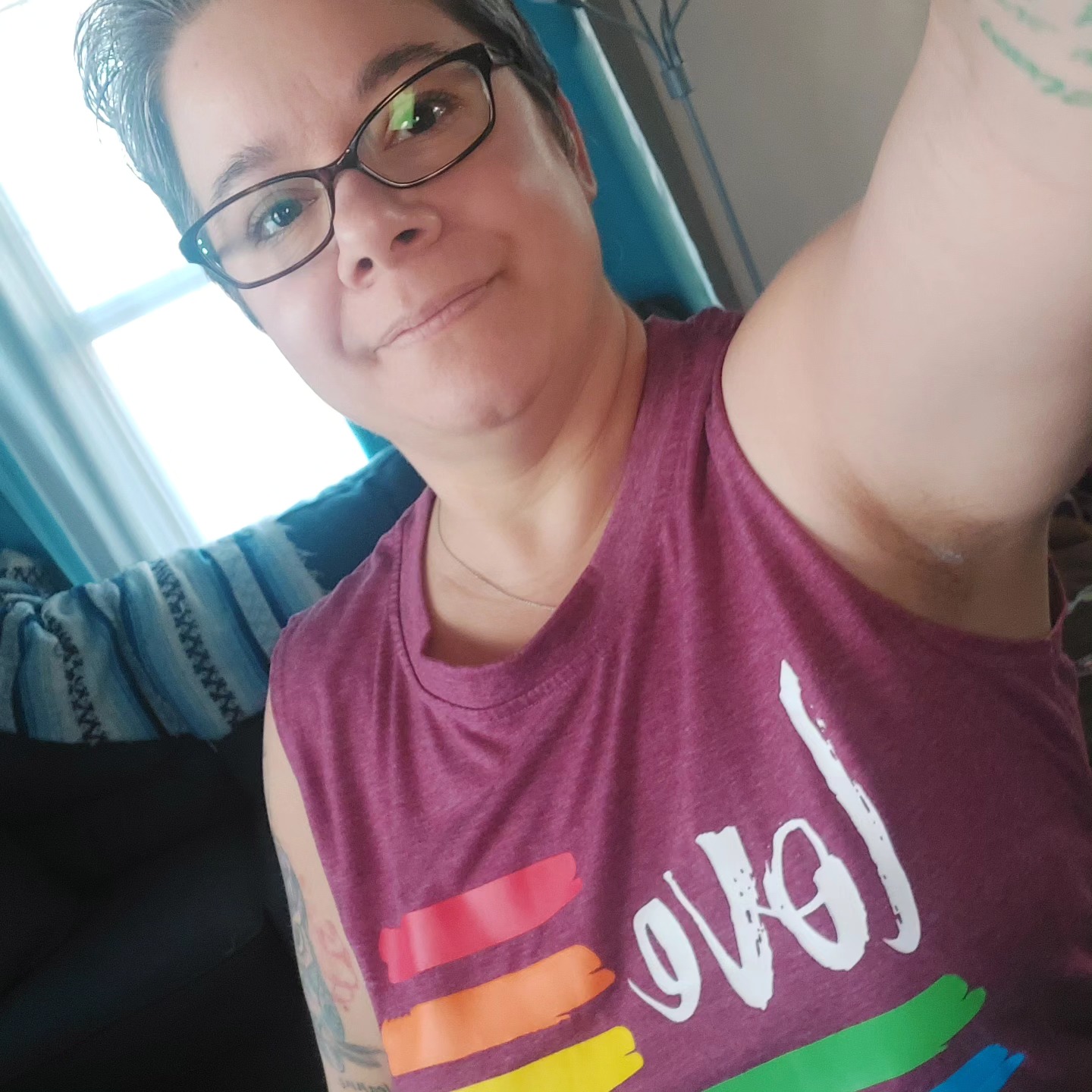 Brenda Feinen, a smiling white woman with short dark hair and glasses, wearing  t-shirt with the American flag represented by the word 
