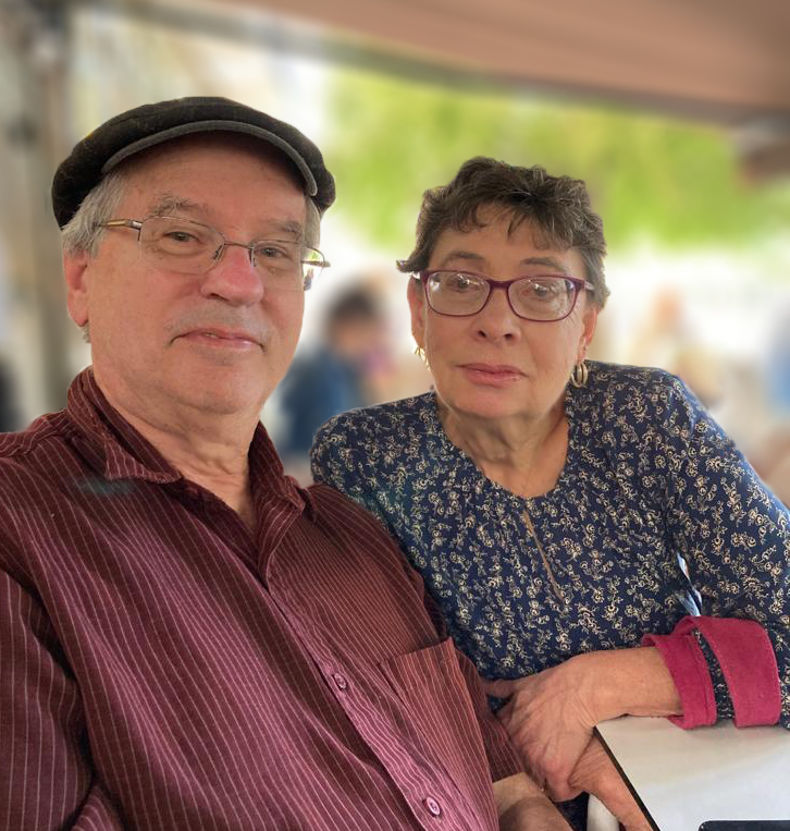 Bob and Joyce Carlson, a white man and woman with glasses seated at an outdoor cafe