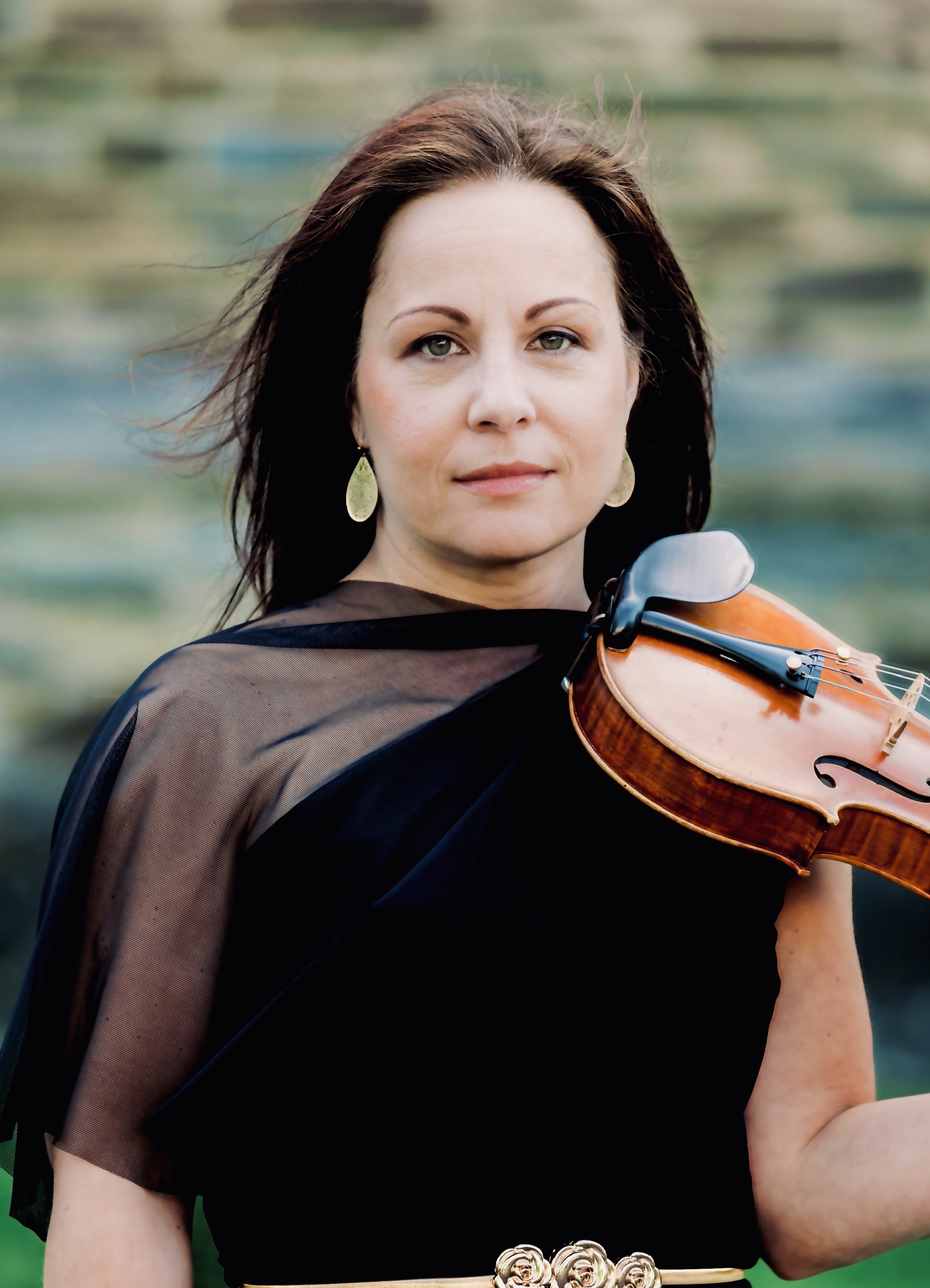 Debrah Devine, a white woman with long brown hair in a brown velvet and chiffon top holding a violin
