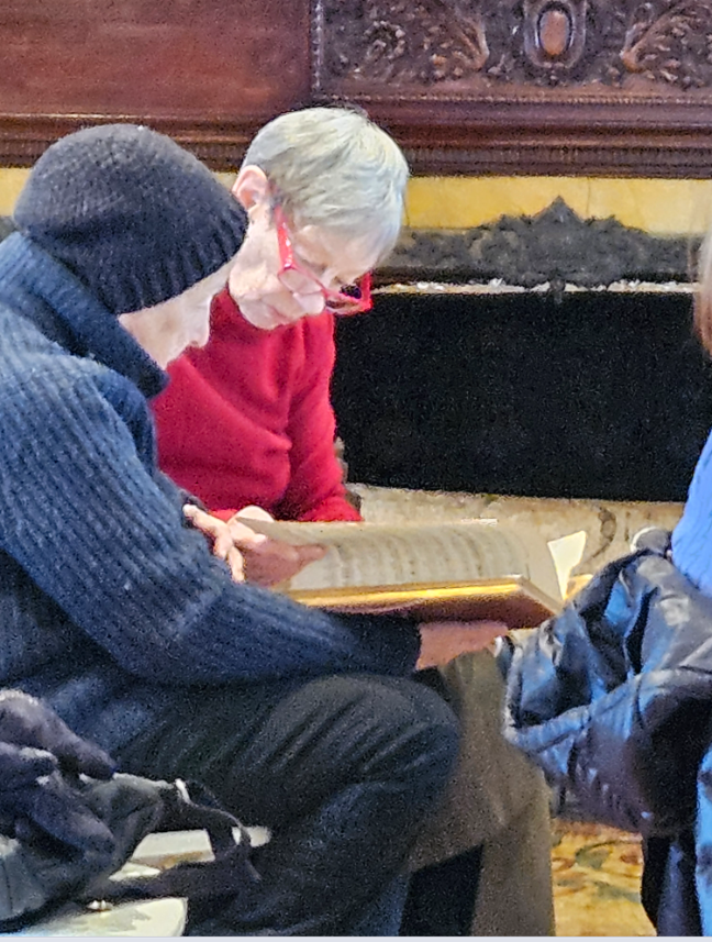 Two white women with short gray hair examine a music score at the Kilmer Mansion