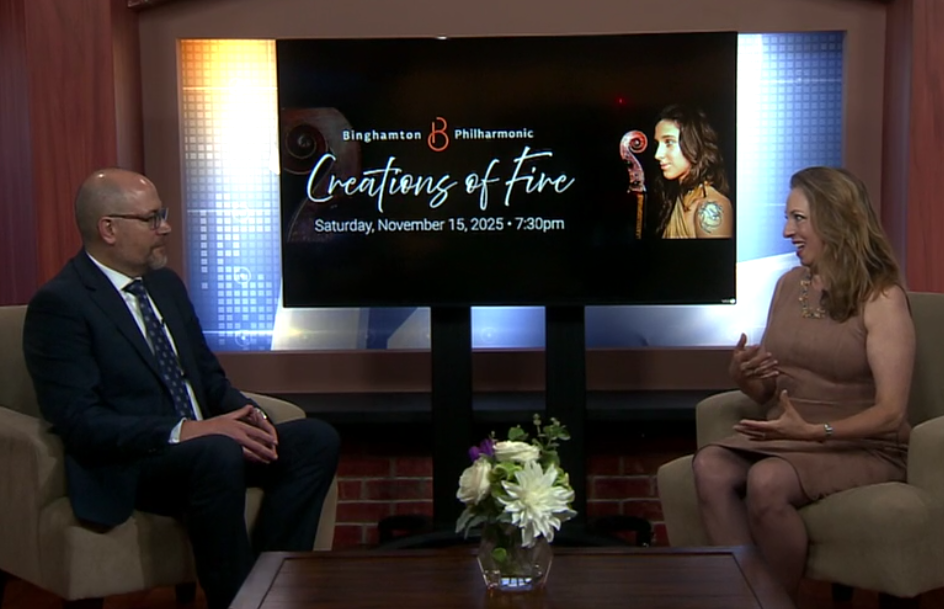 Paul Cienniwa, a bald white man with glasses, and Julia Grella O'Connell, a smiling white woman with long brown hair, sitting in front of a screen with the text 