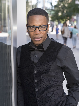 Image: Terrence Willson, piano soloist, an African American man with black glasses on a city street