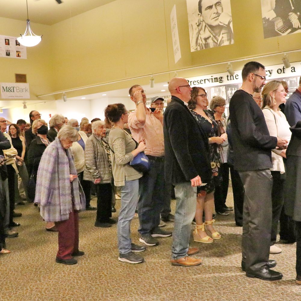 A crowd of people of all ages and genders standing in line in the lobby of the Forum THeatre