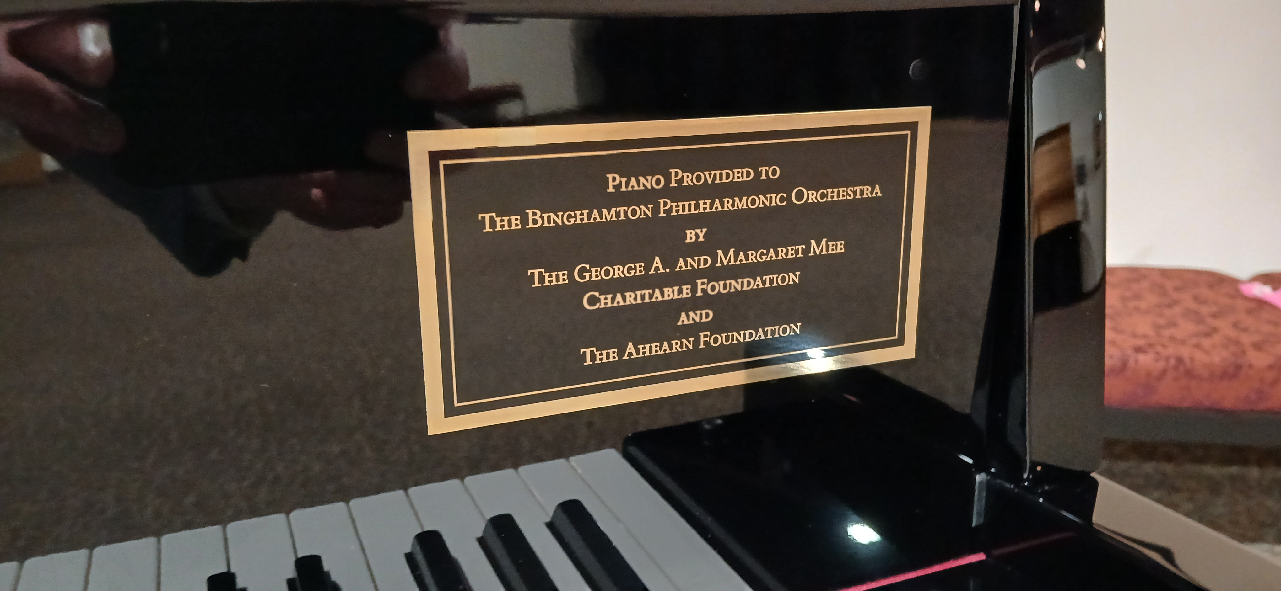 Image of piano keyboard with a gold plaque stating that the piano is a gift to the Philharmonic of the Mee Charitable Foundation and the Ahearn Foundtion