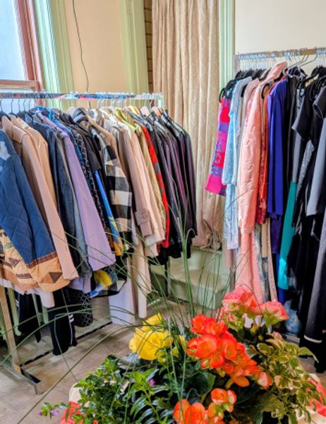 Basket of flowers with clothing on racks behind