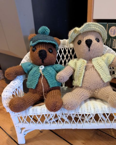 Two handknit stuffed bears on a tiny wicker settee