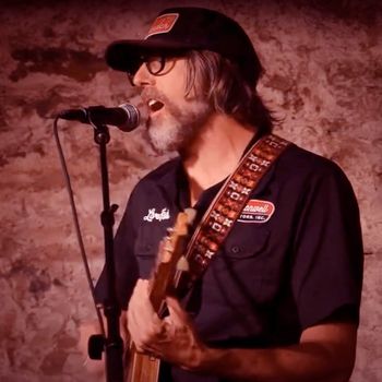 Scott Hall musician and songwriter playing a singing and playing a cigar box guitar live
