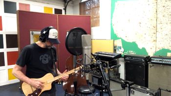 Scott Hall musician and songwriter in the studio holding a three string solid body guitar
