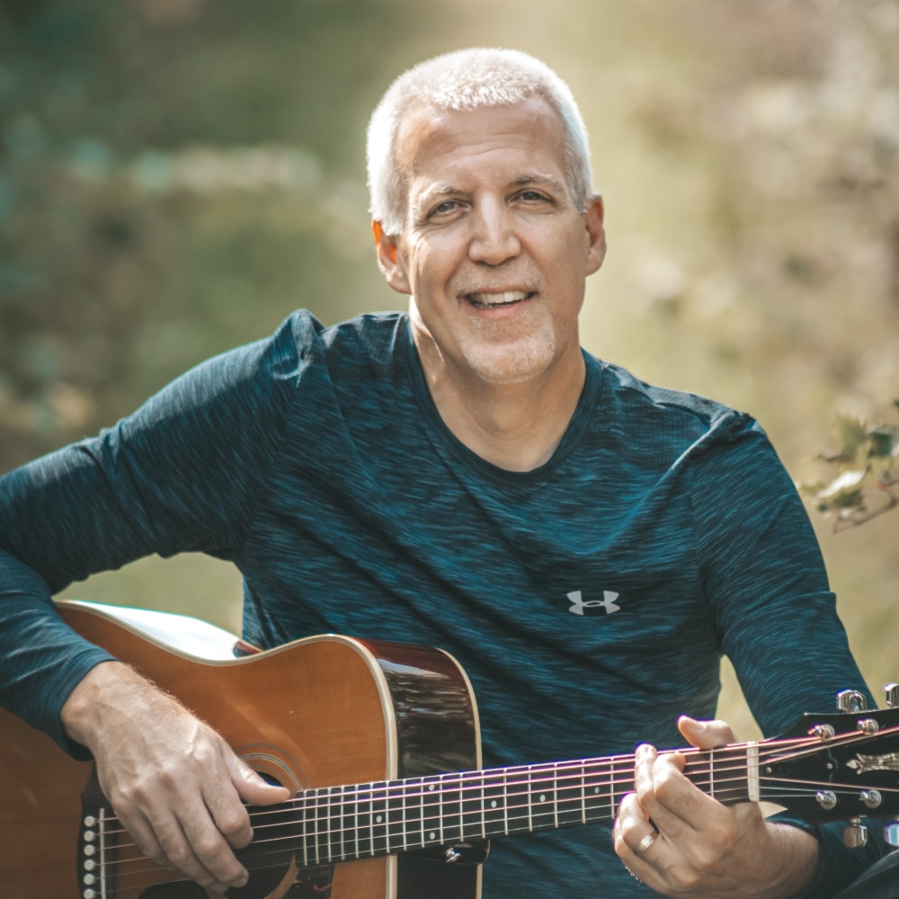 Mike Lucey Sitting in a Vineyard with a Guitar