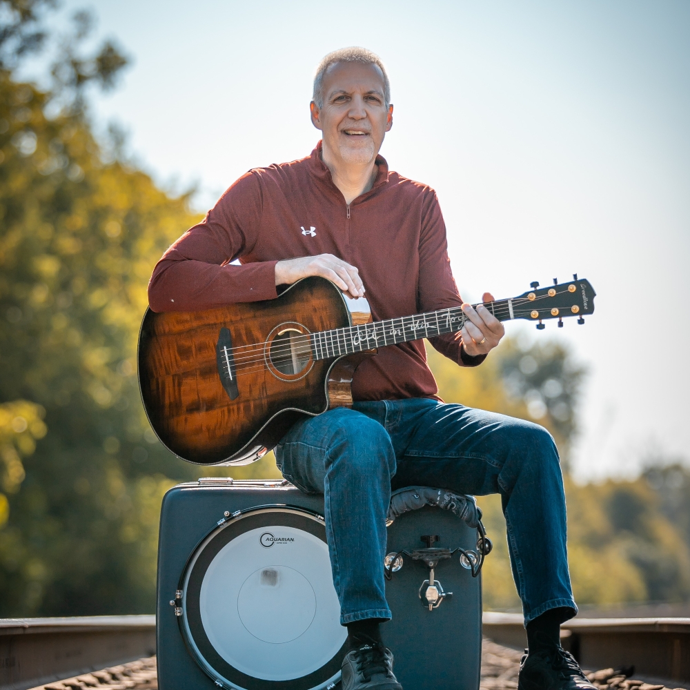 Mike Lucey Sitting on a Suitcase Drum Kit on a Railroad Track