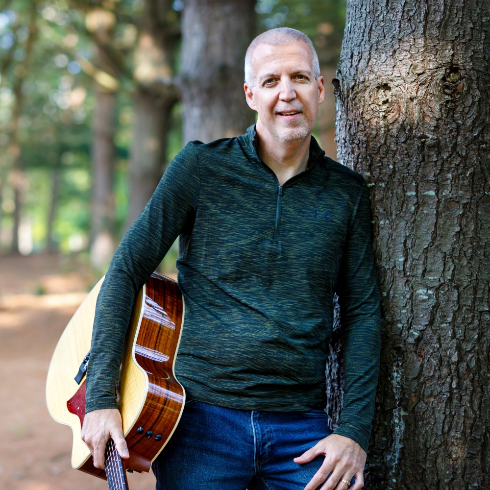 Mike Lucey Leaning on a Tree with a Guitar