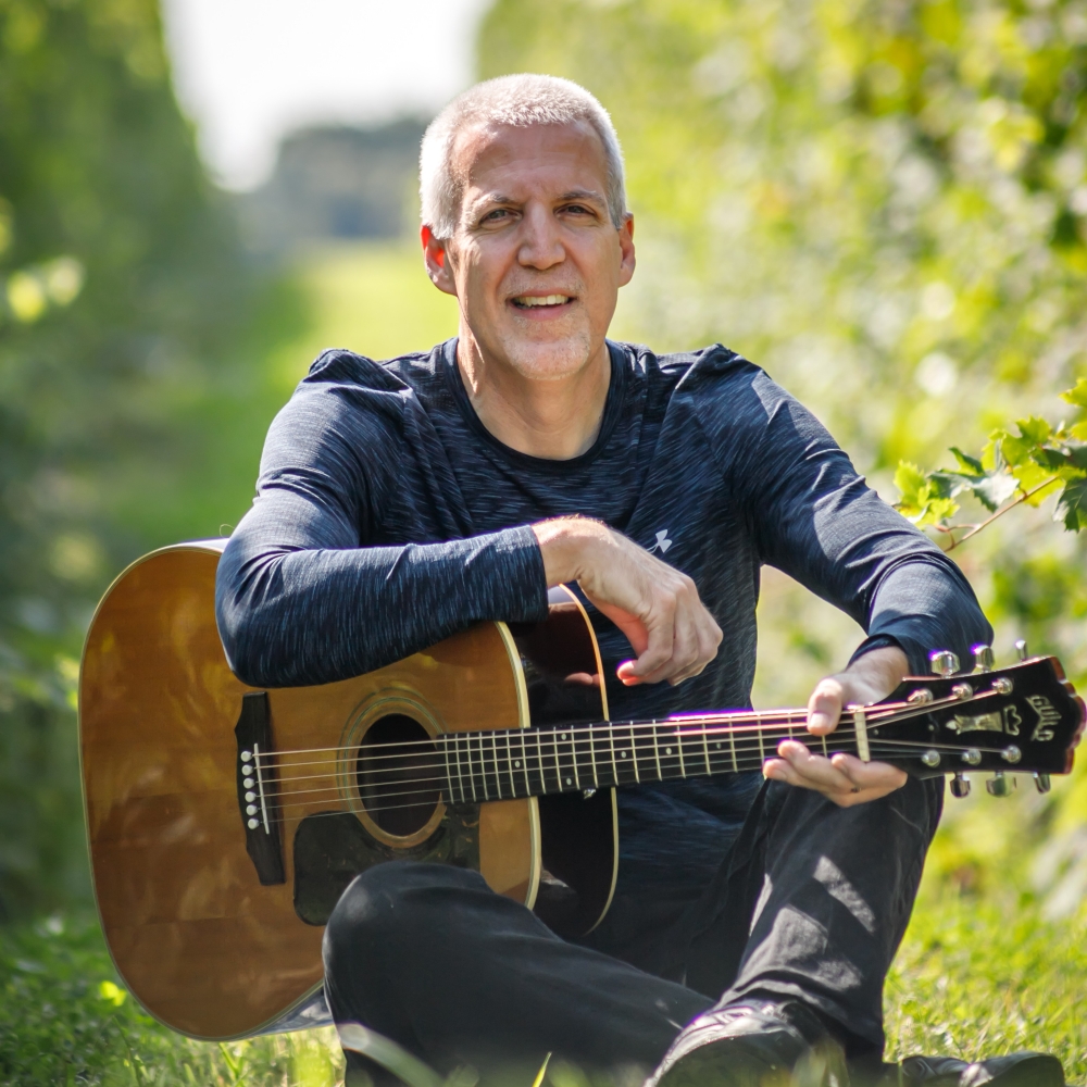 Mike Lucey Sitting on a Blanket in a Vineyard