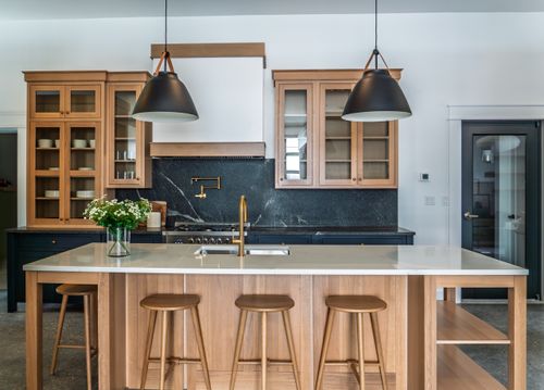 Our DeWils kitchen display features a perimeter of paint-grade maple in a Ponderosa finish, anchored by a central island and glass wall cabinetry crafted from Quartersawn White Oak