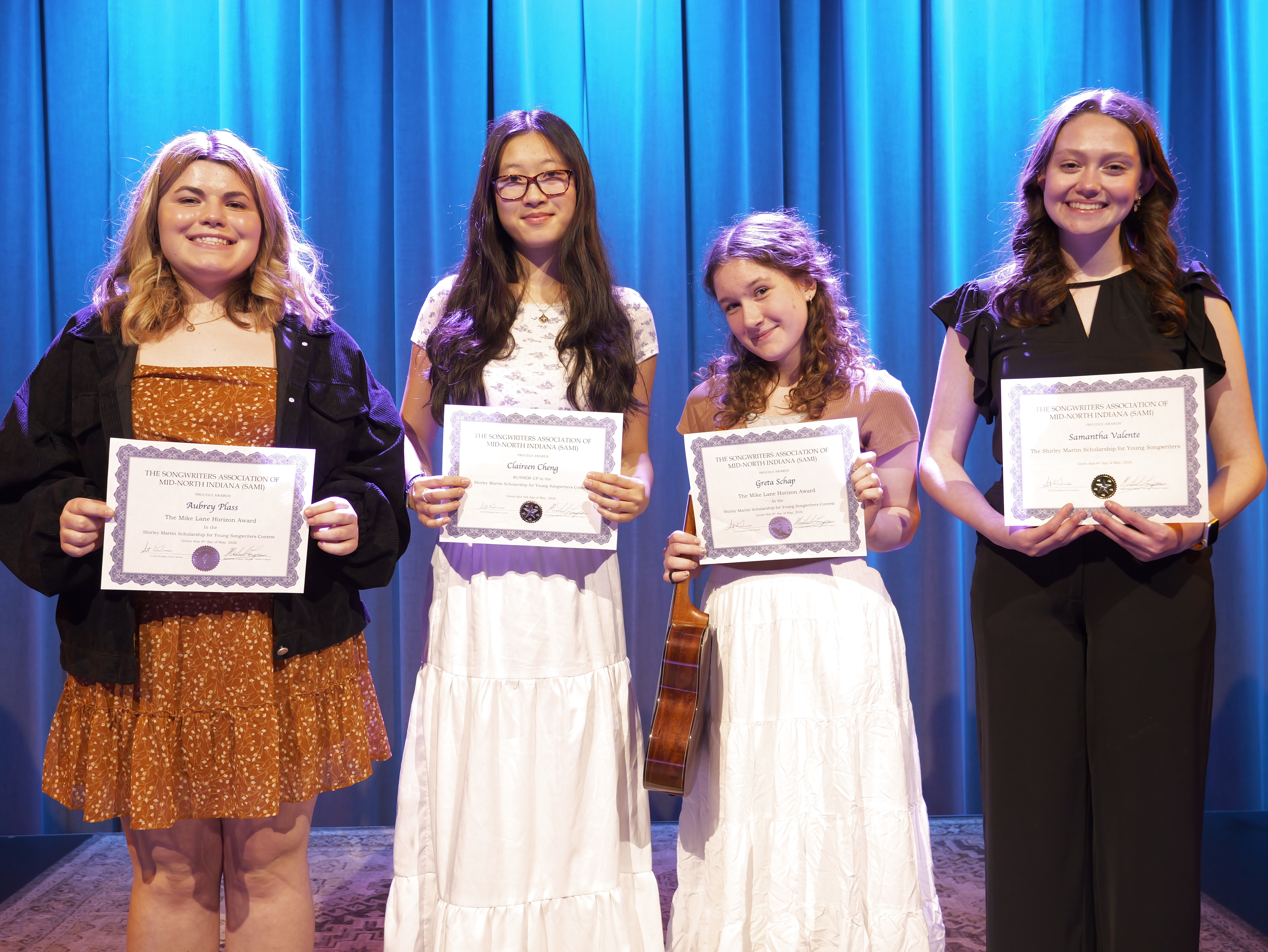 Four young women show off their certificates on stage