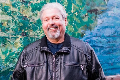 Bryan Metzger smiling in front of a mural