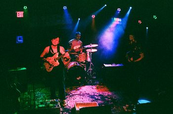 Margot Biever (she/her) on guitar, Ian Strobino (he/him) on drums, and Zach Goforth (he/him) on bass together as Together Breakfast at The East Room.
