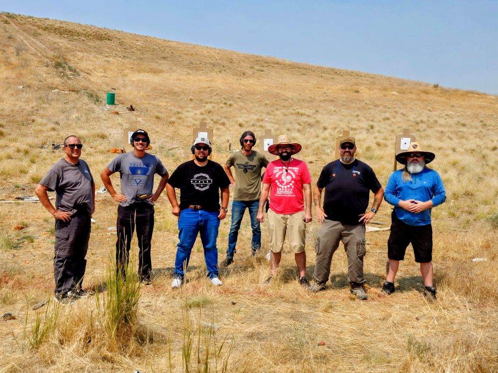 Seven adult males standing in the desert posing for a group Photo after a practical concealed class