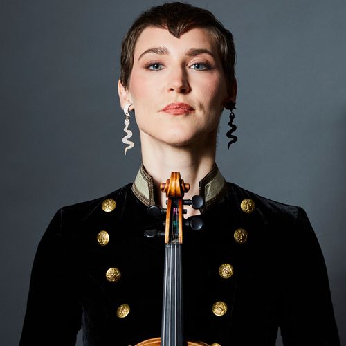 Portrait of Geo Hathaway of Medusa Quartet with fiddle, dressed in black and gold.