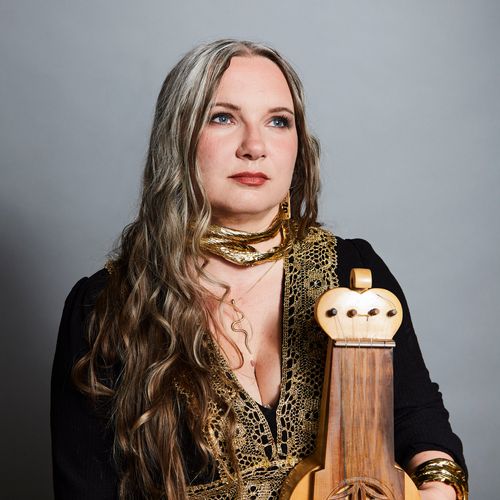 Portrait of Marta Sołek of Medusa Quartet posing with a suka, wearing black and gold.