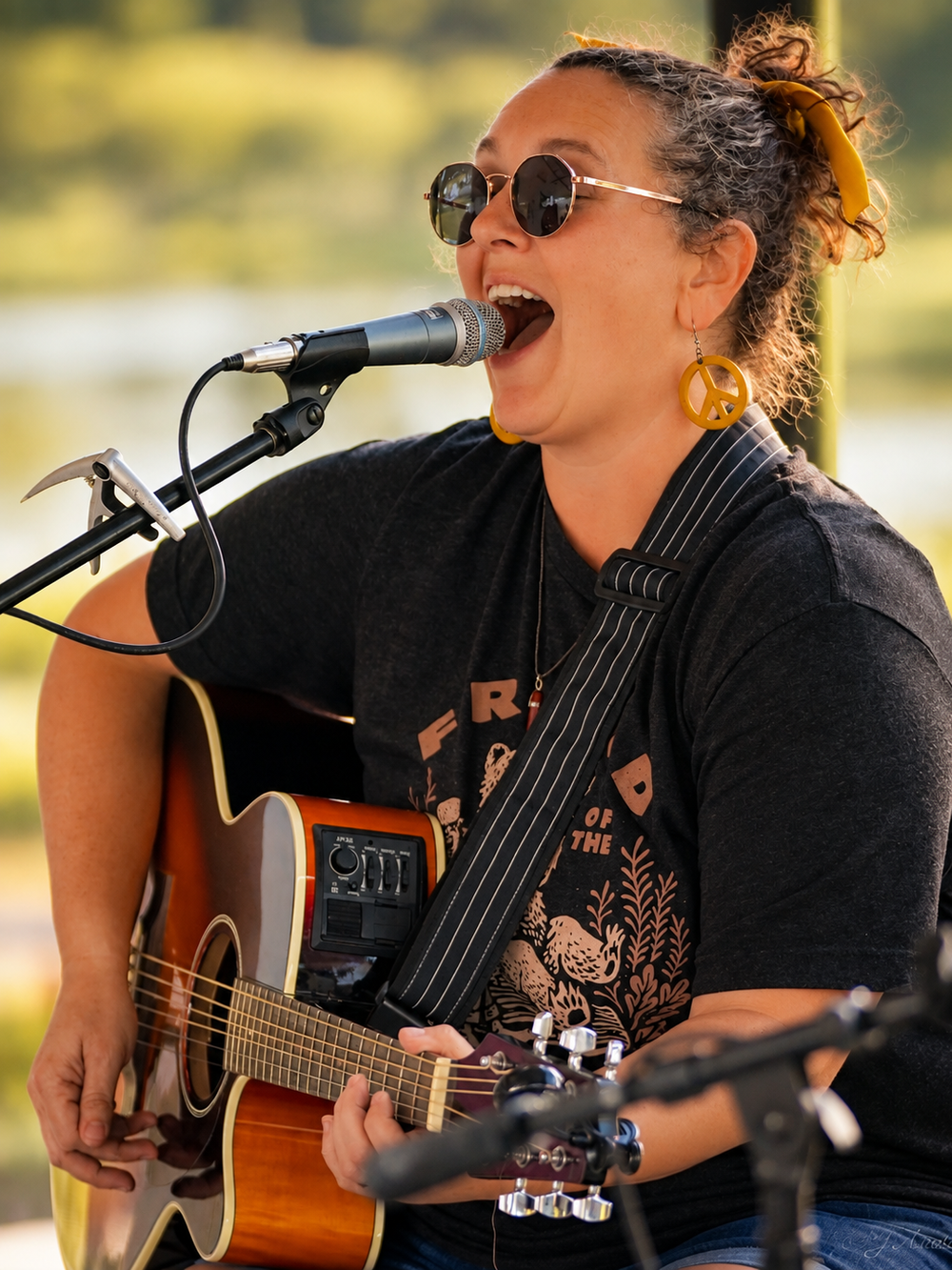 Jen Anders singing and playing acoustic guitar at an outdoor live performance