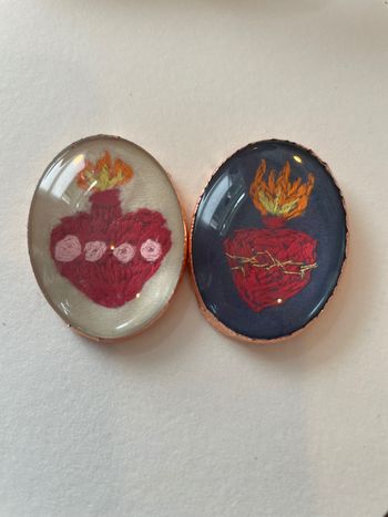 Embroidered Sacred and Immaculate Hearts on velvet under watchglass
