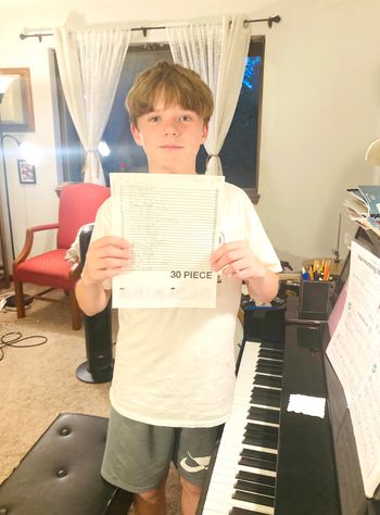 In this photo, my beginner piano student celebrates the completion of his 30-piece challenge this summer!
