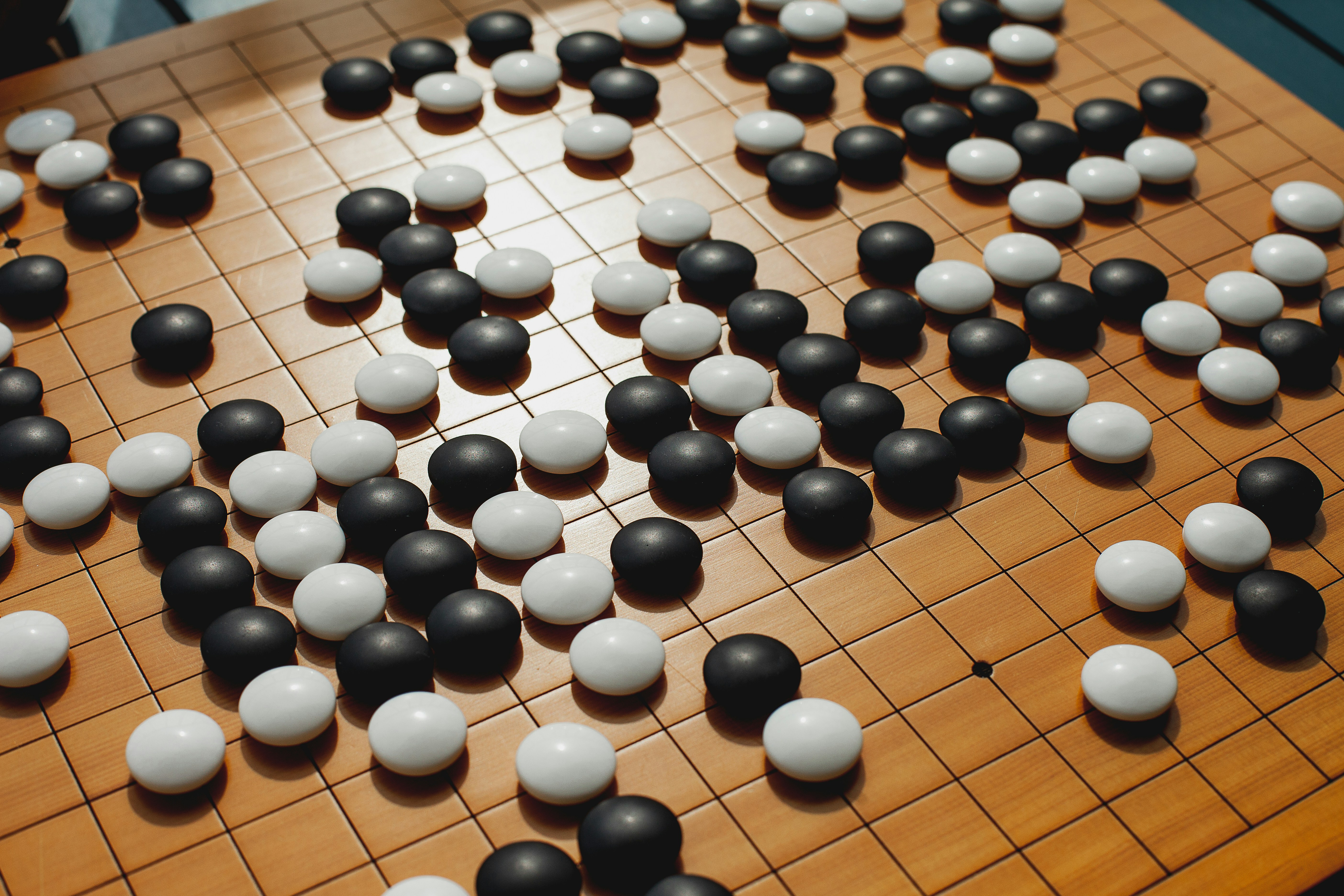 wooden board scored with a grid, with black and white stones