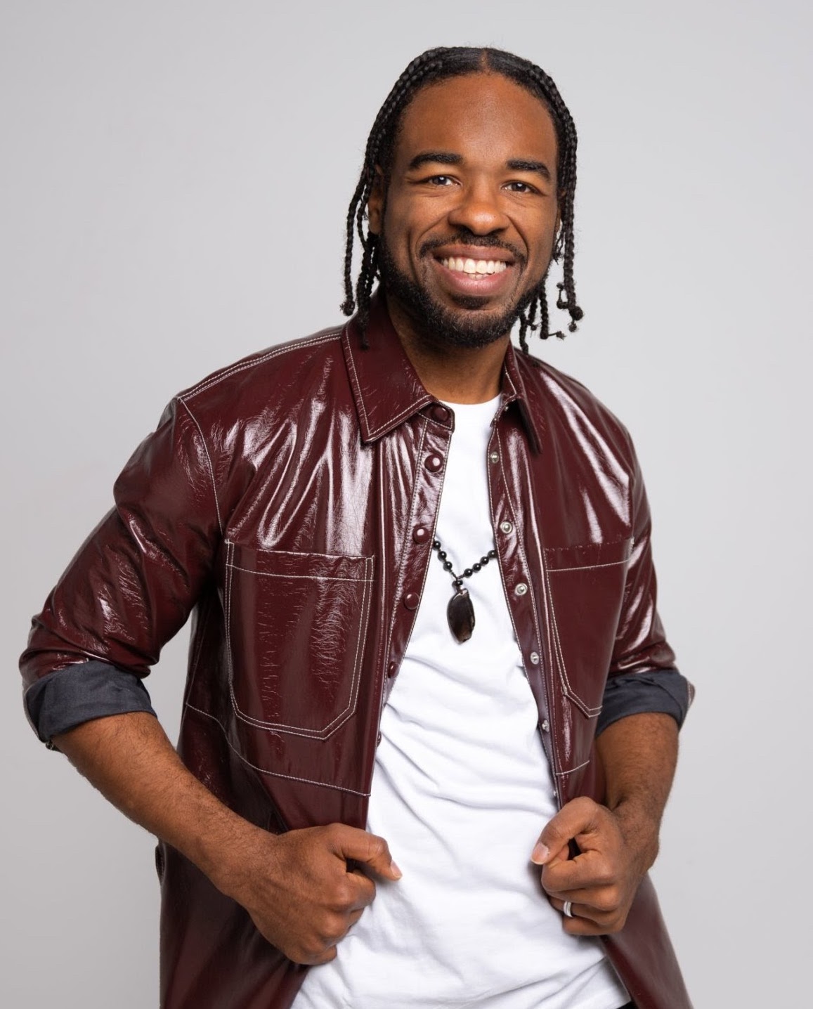 Adrian Black smiling in a burgundy jacket over a white shirt.